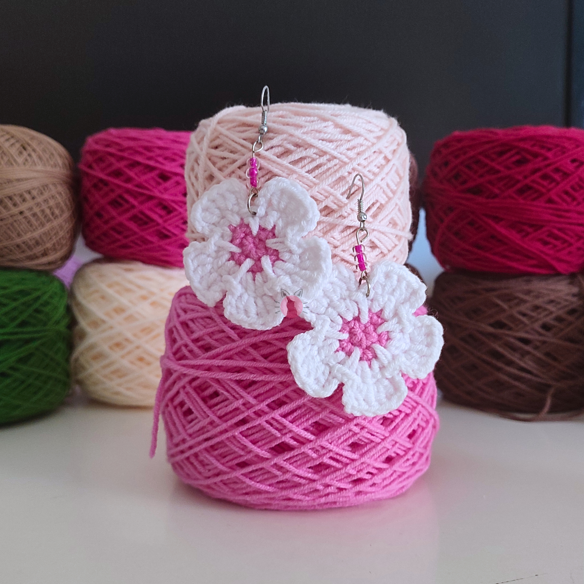 handmade crochet flower earrings displayed on yarn