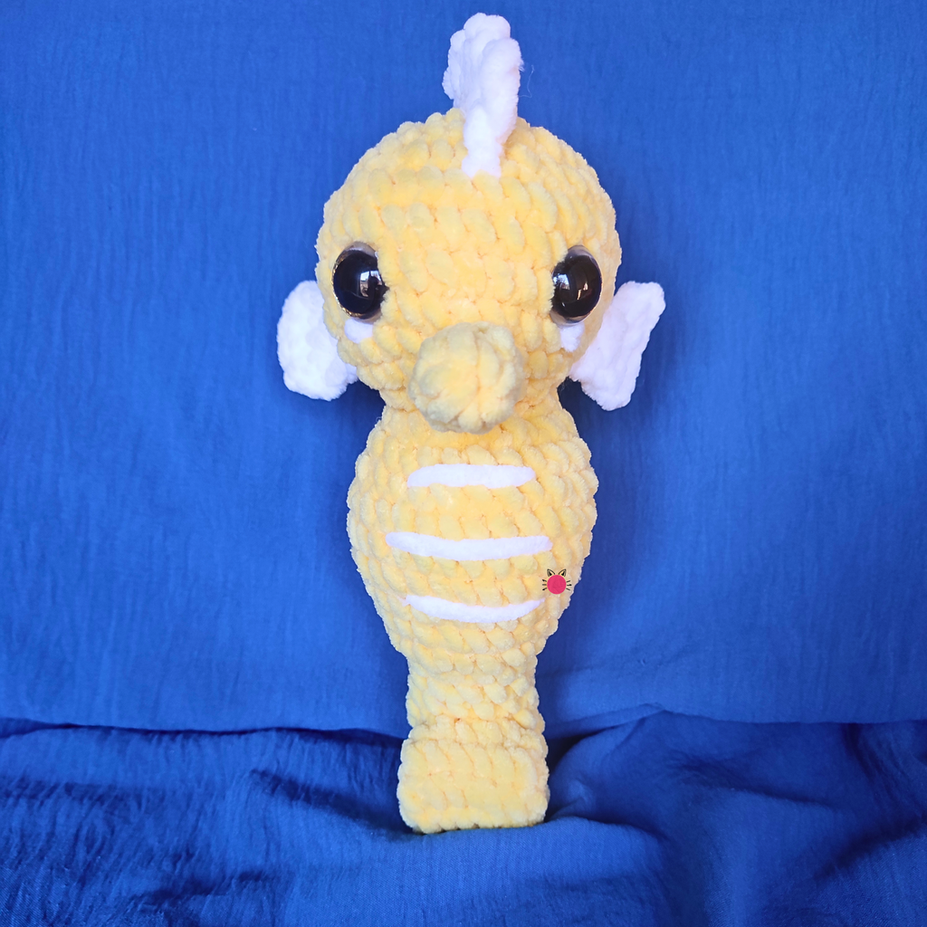 Yellow crochet plush toy with a white horn on a blue background
