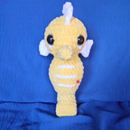 Yellow crochet plush toy with a white horn on a blue background